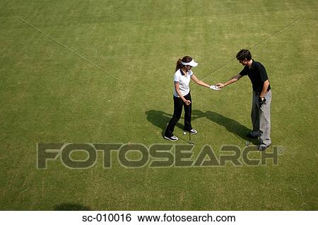Stock Photograph - Man passing a golf ball to a woman. Fotosearch