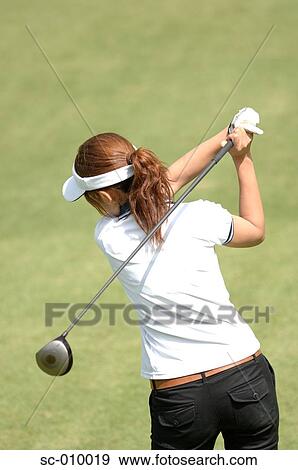 Rear view of a female golfer playing a shot View Large Photo Image Stock Photo - Rear view of a female golfer playing a shot. Fotosearch