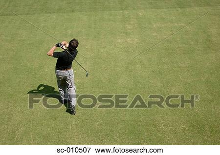 Stock Photo - Rear view of a male golfer playing a shot. Fotosearch