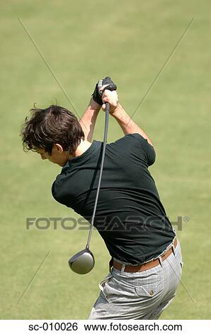 Stock Photograph - Rear view of a male golfer playing a shot. Fotosearch