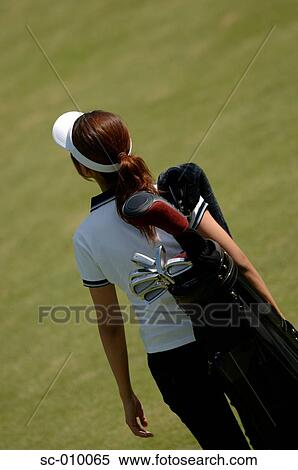 Stock Photography - Rear view of a woman carrying a golf bag. Fotosearch