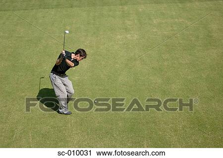 Stock Image - Side view of a male golfer playing a shot. Fotosearch