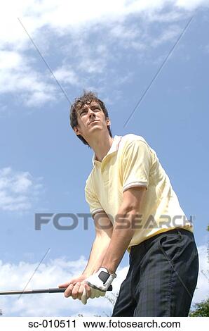 Stock Image - Side view of a man playing a golf shot. Fotosearch