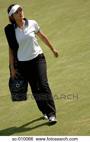 Stock Photograph - Side view of a woman carrying a golf bag. Fotosearch