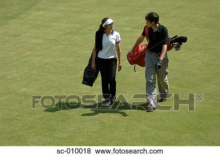 Stock Photo - Side view of man and a woman carrying their golf bags. Fotosearch