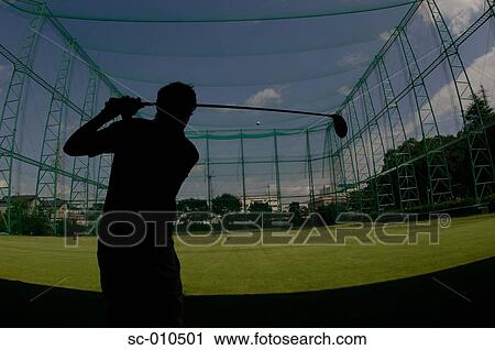 Stock Image - Silhouette of a man playing a golf stroke at a golf range. Fotosearch