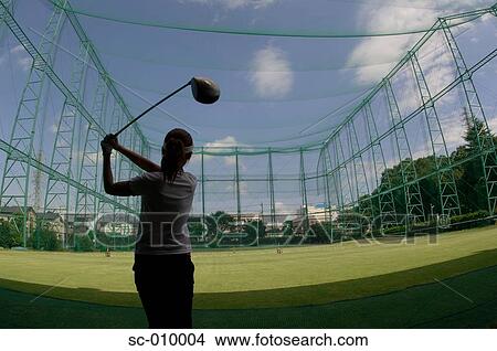 Picture - Woman playing a golf stroke at a golf range. Fotosearch