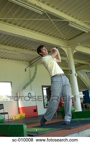 Stock Photo - Young man playing a golf shot. Fotosearch