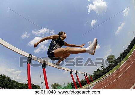 Stock Image - Male Runner Clearing a Hurdle. Fotosearch