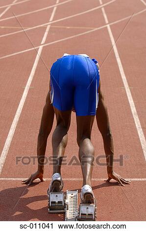 Stock Image - Male Runner Crouched On Starting Blocks. Fotosearch