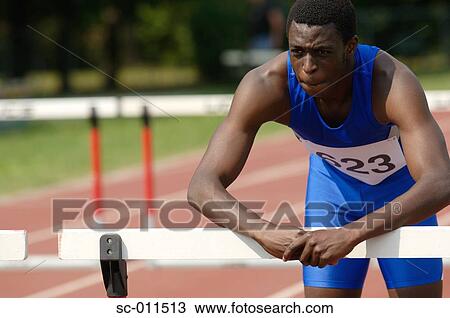 Stock Image - Male Runner Leaning Against a Hurdle. Fotosearch