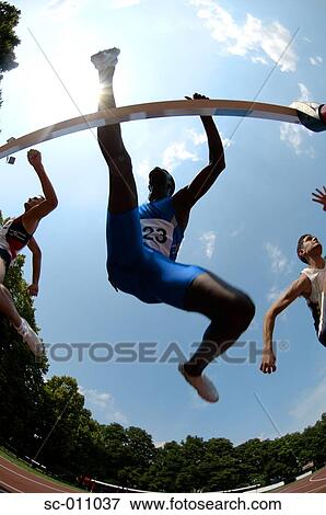 Stock Photo - Male Runners Clearing Hurdle. Fotosearch