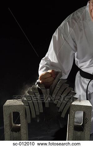 Stock Image - Blackbelt Breaking a Stack of Concrete Blocks. Fotosearch