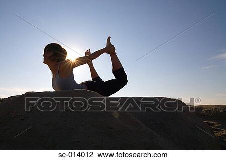 Stock Image - Silhouetted young woman exercising. Fotosearch