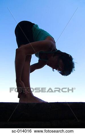 Stock Photograph - Silhouetted young woman exercising. Fotosearch
