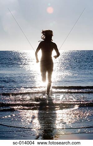Silhouetted young woman running into sea View Large Photo Image Picture - Silhouetted young woman running into sea. Fotosearch