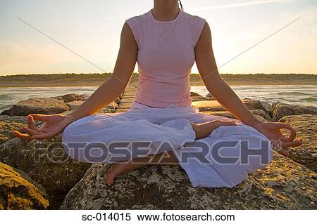 Stock Photography - Young woman doing yoga exercises by sea. Fotosearch