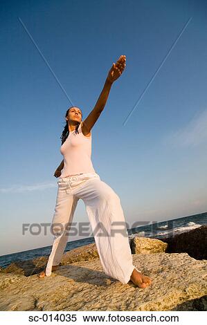 Stock Photography - Young woman doing yoga exercises by sea. Fotosearch