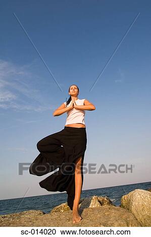 Young woman doing yoga exercises on rock View Large Photo Image Stock Image - Young woman doing yoga exercises on rock. Fotosearch
