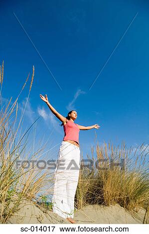 Stock Photo - Young woman exercising on sand dune. Fotosearch