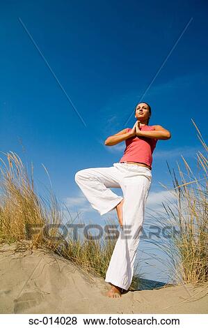 Young woman exercising on sand dune View Large Photo Image Stock Photo - Young woman exercising on sand dune. Fotosearch