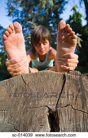 Stock Photo - Young woman exercising on tree trunk. Fotosearch