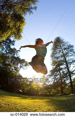 Stock Photo - Young woman jumping in park. Fotosearch
