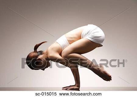 Stock Photography - Young Asian woman in crow pose. Fotosearch