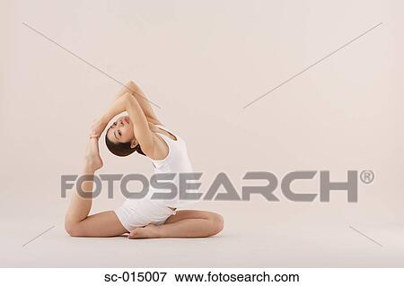 Stock Photo - Young Asian woman in Full One-Legged King Pigeon yoga position. Fotosearch
