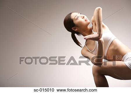 Stock Image - Young Asian woman in yoga position. Fotosearch