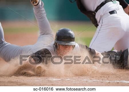 Stock Photograph - Baseball player sliding into home plate. Fotosearch