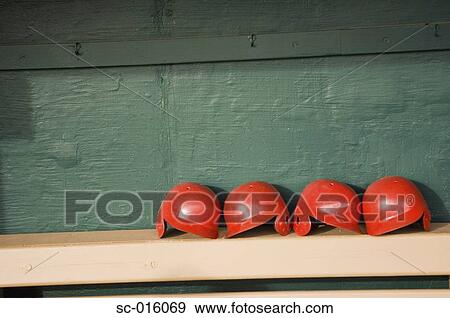 Stock Photo - Batting helmets on a bench in a dugout. Fotosearch