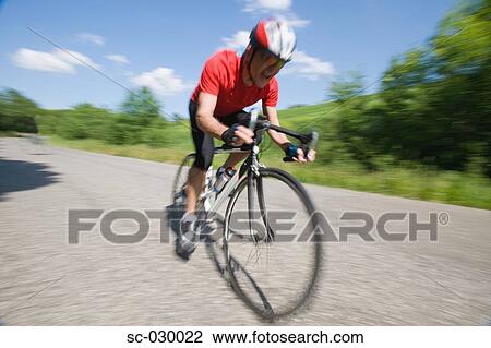 Stock Image - Cyclist cycling on road, blurred, motion. Fotosearch