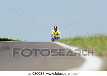 Stock Image - Cyclist riding bicycle, front view. Fotosearch
