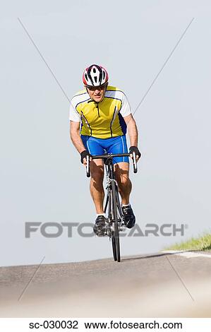 Stock Image - Cyclist riding bicycle, front view. Fotosearch