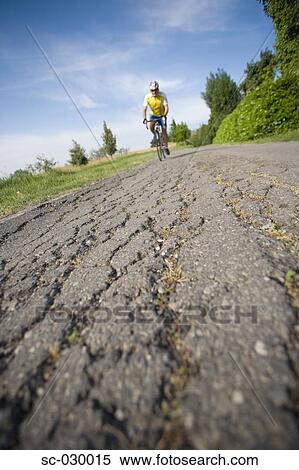 Cyclist riding bicycle on a cracked road, front view View Large Photo Image Stock Photography - Cyclist riding bicycle on a cracked road, front view. Fotosearch
