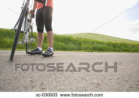 Stock Image - Cyclist with bike, low section. Fotosearch