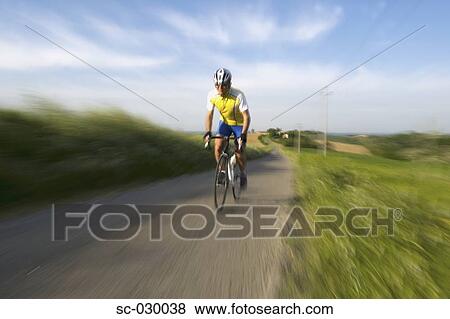 Stock Photo - Front view of a man cycling on road. Fotosearch