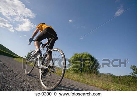 Stock Image - Rear view of a man riding bike. Fotosearch