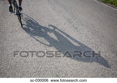 Shadow of a bicyclist casting on road View Large Photo Image Stock Photograph - Shadow of a bicyclist casting on road. Fotosearch