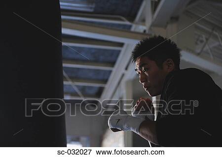 Stock Photo - Japanese boxer practicing with punching bag. Fotosearch