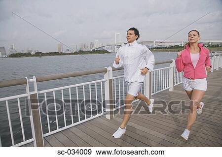 Stock Photo - Young couple jogging on bridge. Fotosearch