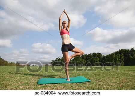 Picture - Young Woman doing the tree pose on mat. Fotosearch