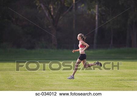 Young Woman in tank top jogging on grass View Large Photo Image Stock Image - Young Woman in tank top jogging on grass. Fotosearch