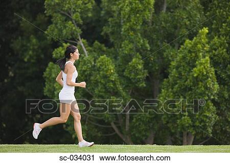 Young Woman in tank top jogging on grass View Large Photo Image Stock Image - Young Woman in tank top jogging on grass. Fotosearch
