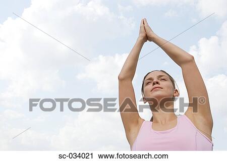 Stock Image - Young Woman meditating in a tree pose. Fotosearch