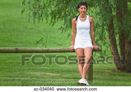 Young Woman sitting on log near tree View Large Photo Image Stock Image - Young Woman sitting on log near tree. Fotosearch