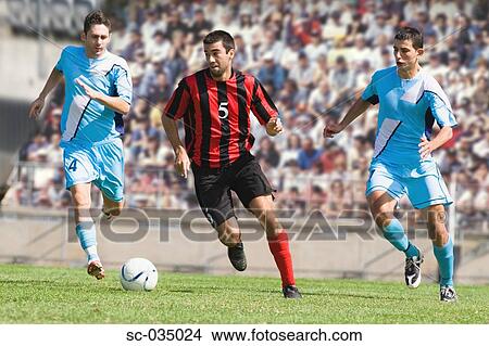 Picture - Three soccer players challenging for ball. Fotosearch