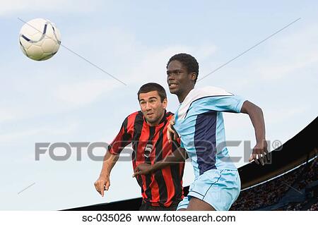 Stock Photograph - Two soccer players challenging for the ball. Fotosearch