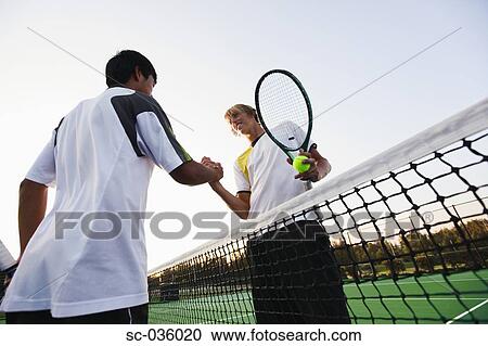 Stock Image - Two tennis players shaking hands at net. Fotosearch